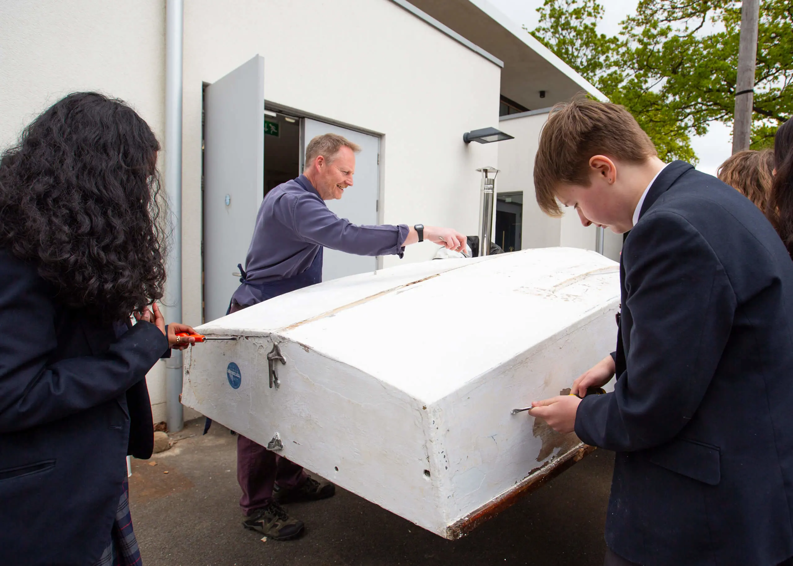 Ryde School Senior pupils and teacher painting the hull of a sailing boat